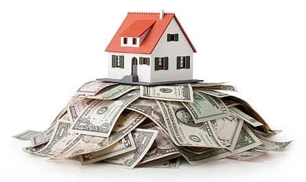 Miniature house sitting atop a pile of cash, representing home financing